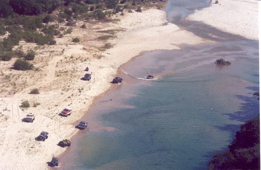 [Many vehicles in the river bottom showing long mud contrails under the water - as seen from high above]